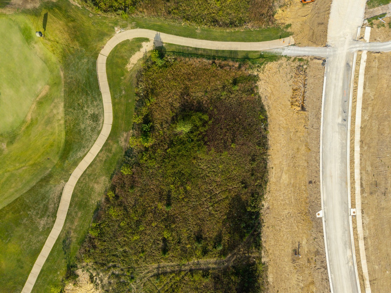 Winding concrete walking path through grassy park