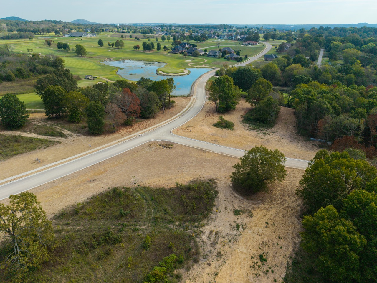 Winding road through barren hillside with scattered trees.