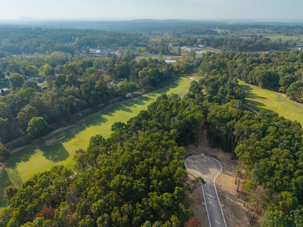 Aerial view of golf course with winding fairways and trees.