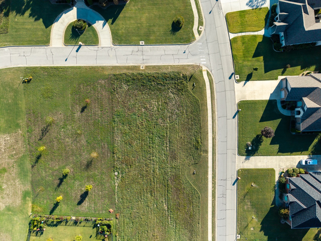 Aerial view of suburban intersection with curved streets and lawns