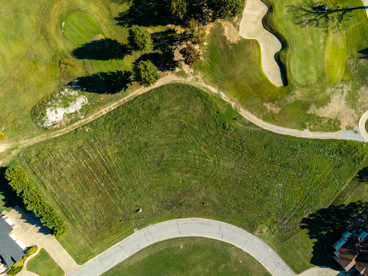 Aerial view of golf course with green and sand bunker.