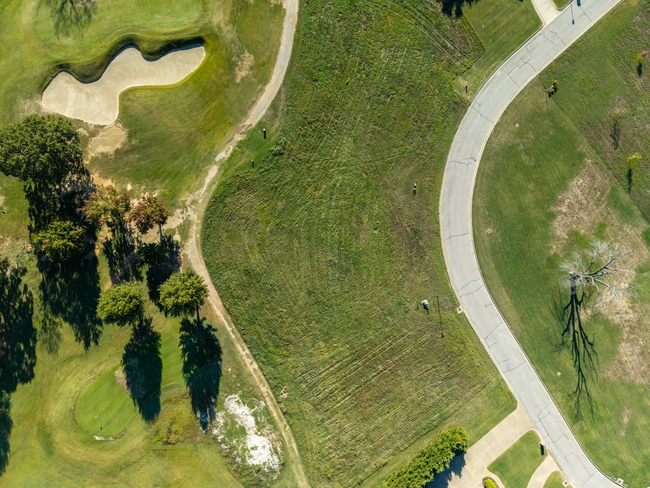 Aerial view of golf course with sand bunker and curved path