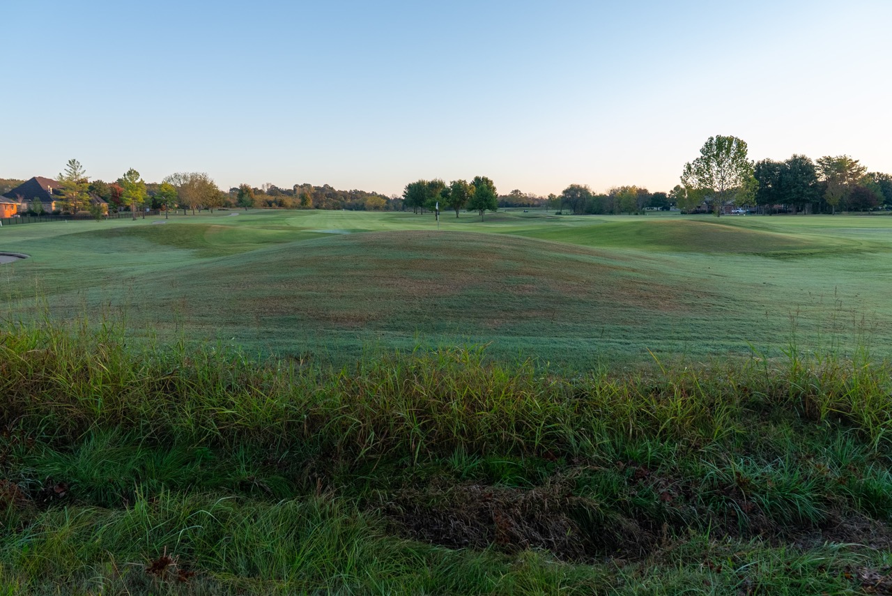 Golf course green with flag and rolling mounds