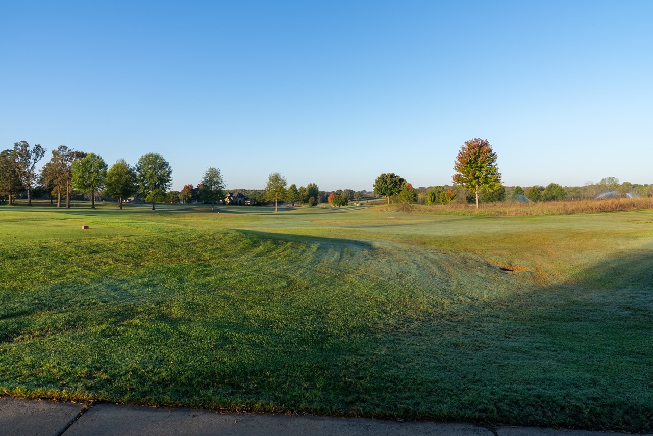 Golf course fairway under blue sky.