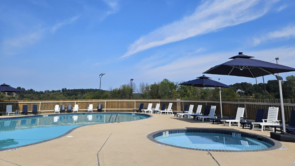 Outdoor swimming pool surrounded by lounge chairs and umbrellas.