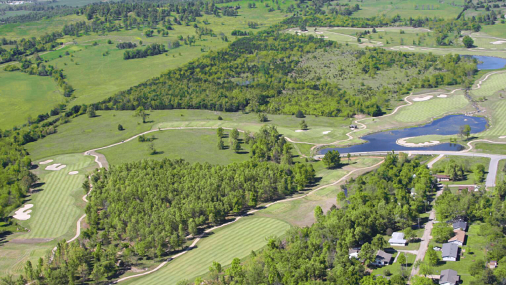 Aerial view of golf course with greens, sand traps, ponds.