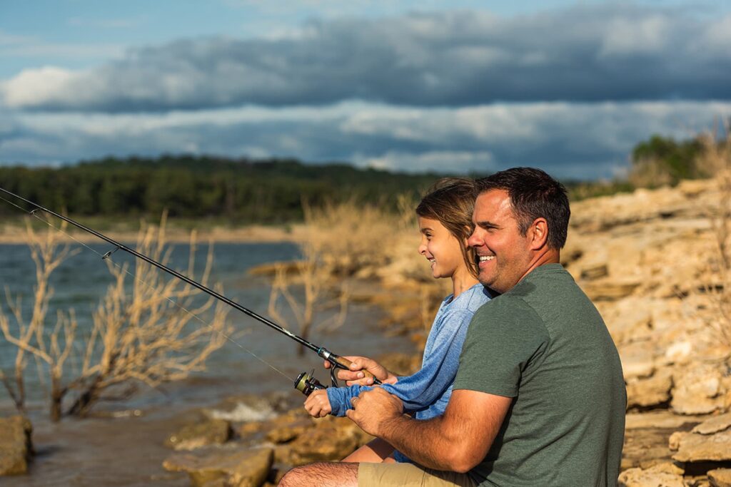 Man and girl fishing by rocky shore