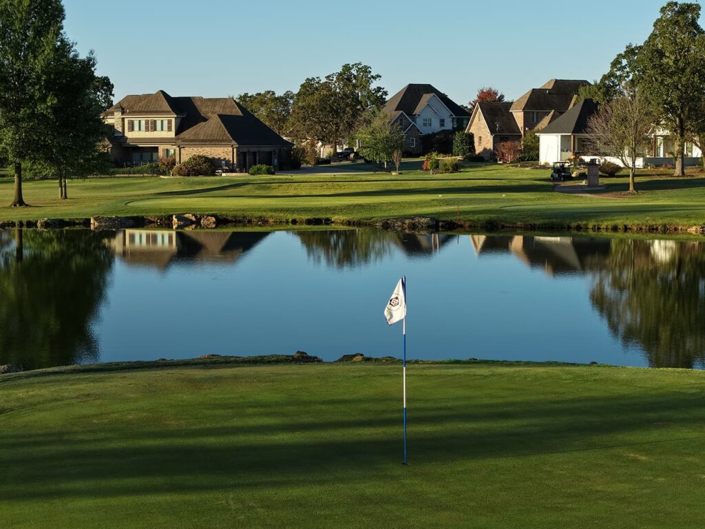 Golf flag on green by pond.