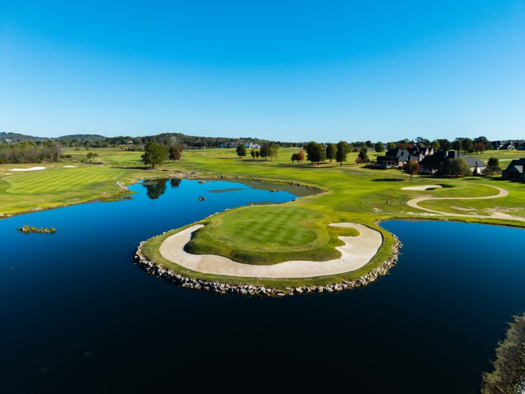 Island green on a golf course surrounded by water.