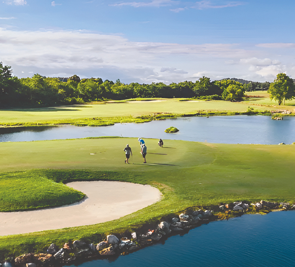 Golfers on putting green beside sand bunker.