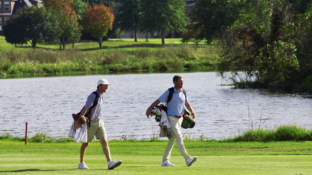 Two golfers carrying golf bags