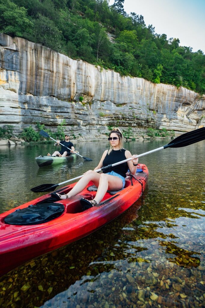 Woman paddling red kayak on calm river