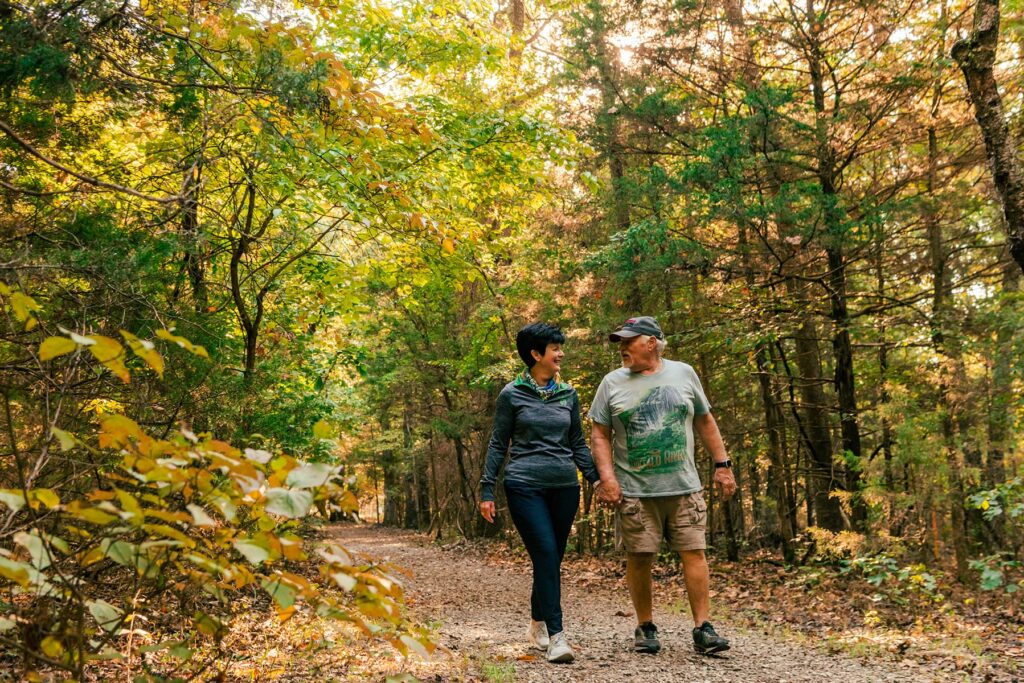 Couple walking hand in hand along forest trail